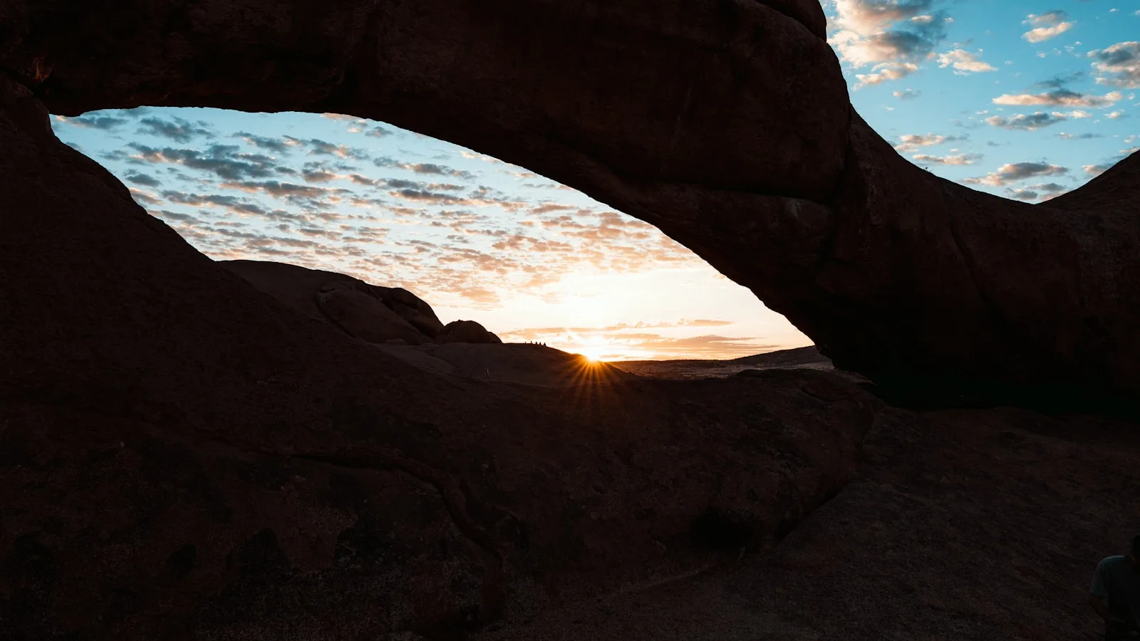 Natural rock arch silhouetted against a sunset sky