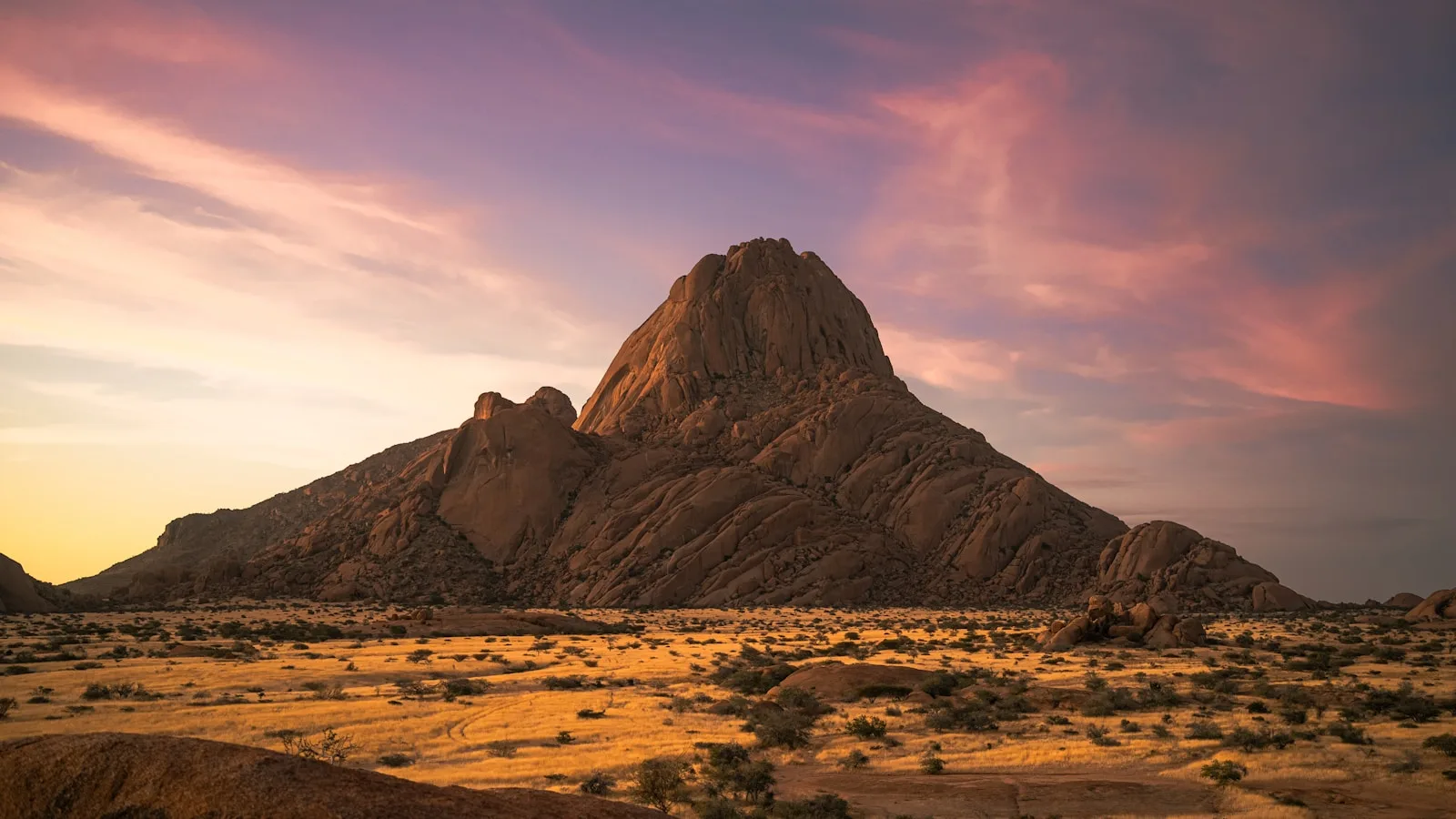 Desert mountain at sunset under a purple and gold sky